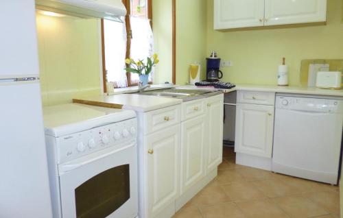 La cuisine est équipée de placards blancs et d'un four avec plaques de cuisson blanches. dans l'établissement 3 Bedroom Cozy Home In Brucheville, à Brucheville