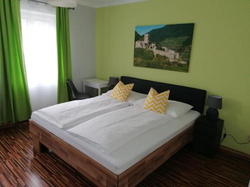 1 dormitorio con 1 cama blanca grande con almohadas amarillas en Gästehaus Ruinenblick, en Spitz