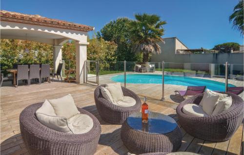 a patio with wicker chairs and a table and a pool at Cozy Home In Aigues-Mortes With Kitchen in Aigues-Mortes