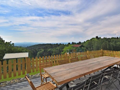 une table en bois avec des chaises et une clôture en bois dans l'établissement Holiday home with panoramic view and every convenience spa, à Waldkirchen