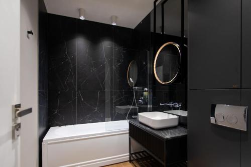 a black bathroom with a tub and a sink and mirror at Vila Avy in Haţeg