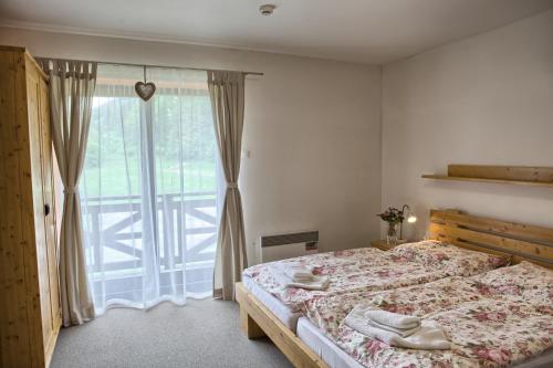 a bedroom with a bed and a large window at Penzion Bystrinka in Tale