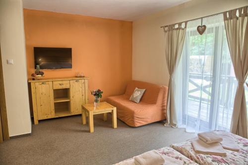 a bedroom with a bed and a tv and a chair at Penzion Bystrinka in Tale