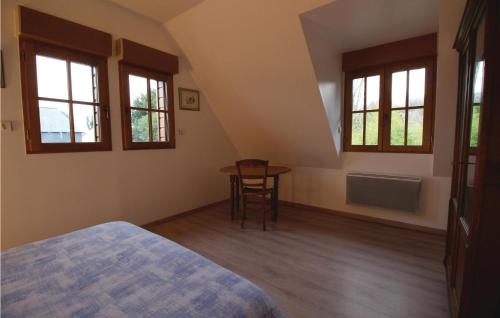 a bedroom with a bed and a table and windows at 2 Bedroom Nice Home In Le Bourg-Dun in Le Bourg-Dun