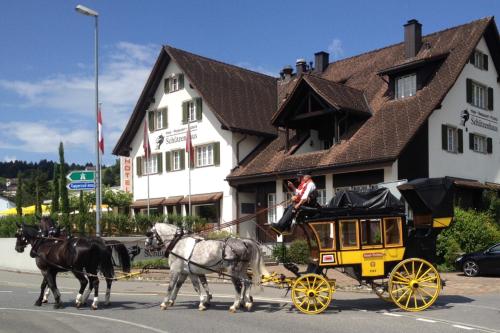 two horses pulling a horse drawn carriage down a street at Hotel Schützenhaus in Uznach