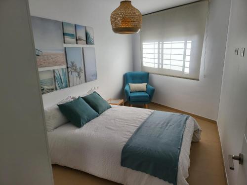 a bedroom with a bed and a blue chair at La Paz del Mediterráneo in Garrucha