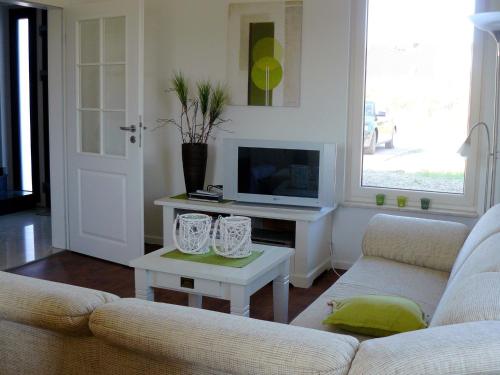 ein Wohnzimmer mit einem Sofa und einem Tisch mit einem TV in der Unterkunft Holiday home in Wietzendorf in the L neburg Heath with a view of the countryside in Wietzendorf