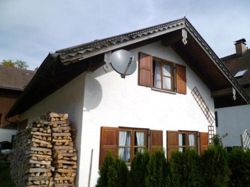 ウンターアンマーガウにあるDelightful Holiday Home in Unterammergauの木製の窓と衛星が備わる白い家