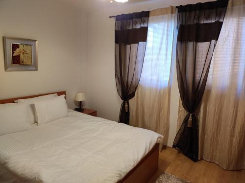 a bedroom with a bed and a window with curtains at Neviasta Apartment in Smolyan