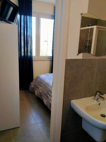 a bathroom with a sink and a bed with a window at Eleonora Bed and breakfast in Muscoline