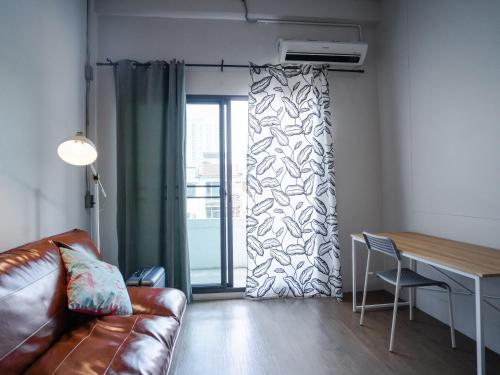 a living room with a couch and a table and a window at Hybrit hostel&cafe in Hat Yai