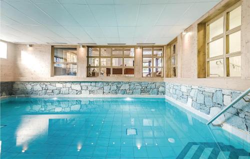 a large swimming pool with blue water in a building at Les Fermes miguy in Les Gets