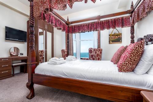 a bedroom with a four poster bed with a window at Riviera Guesthouse in Whitby