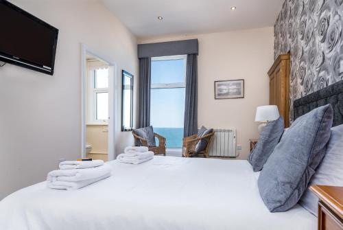 a bedroom with a large white bed with a large window at Riviera Guesthouse in Whitby