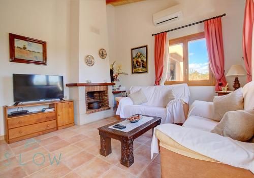 een woonkamer met twee witte banken en een televisie bij Villa Cas Frares by Slow Villas in Santa Maria del Camí