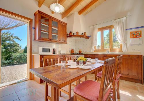 een grote keuken met een houten tafel en stoelen bij Villa Cas Frares by Slow Villas in Santa Maria del Camí