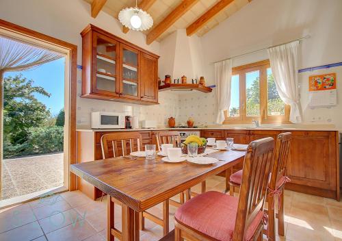 a large kitchen with a wooden table and chairs at Villa Cas Frares by Slow Villas in Santa Maria del Camí