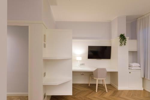 a white room with a desk and a television at Hotel Baylle in Cagliari