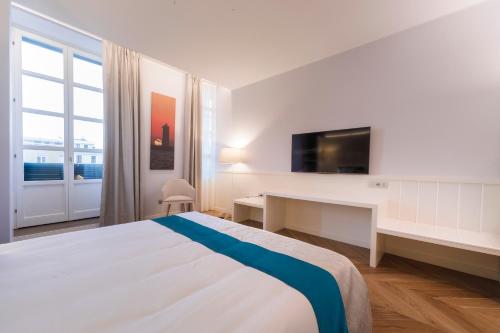 a bedroom with a bed and a desk and a tv at Hotel Baylle in Cagliari