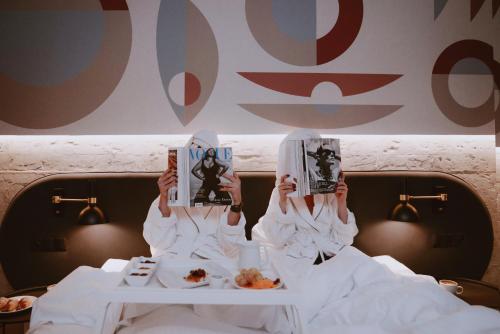 a person reading a book in bed with food at Forest Hotel in Kraków