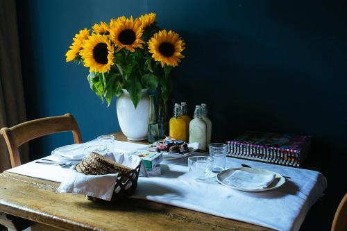een tafel met een vaas met zonnebloemen erop bij B&B Van Gogh Cottage in Nuenen