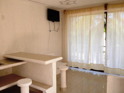 Habitación con mesa, TV y ventana. en QUINTA DIAMANTE Hotel, en Barra Vieja