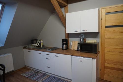 a kitchen with white cabinets and a microwave at UDany Wypoczynek in Wojanów