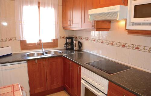 a kitchen with wooden cabinets and a sink and a microwave at Cozy Home In Ses Covetes With Wifi in Ses Covetes