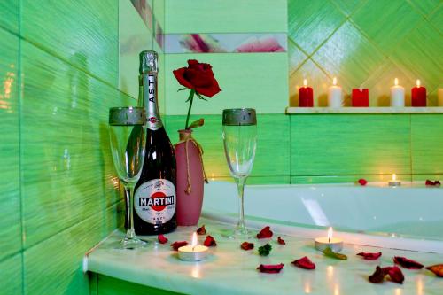 uma casa de banho com uma garrafa de vinho, 2 copos e velas em Sunlion Баунти Hotel em Sochi