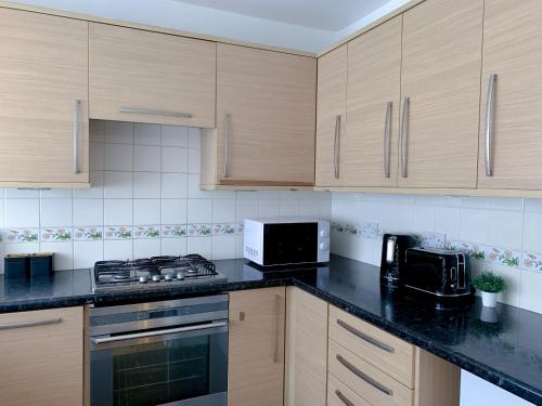 una cucina con armadi in legno e piano di lavoro nero di Large House Near Anfield & Liverpool Town a Liverpool