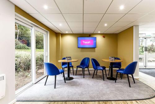 une salle d'attente avec des tables et des chaises et une télévision à écran plat dans l'établissement Days Inn Hotel Fleet, à Fleet