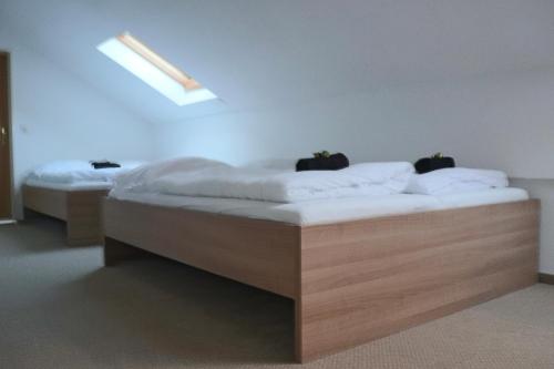 two beds in a room with white sheets and a skylight at FitApartman in Mitterfirmiansreut