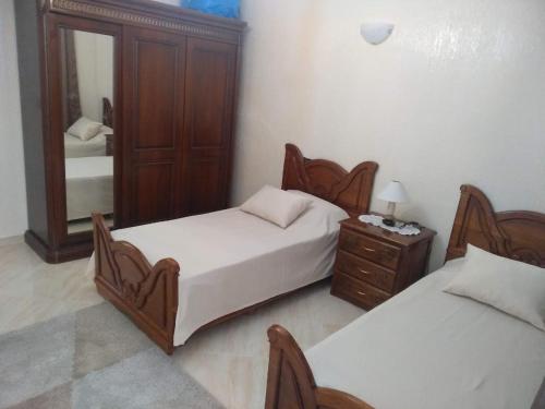 a bedroom with two beds and a dresser and a mirror at Apartment Centre Meknes in Meknès