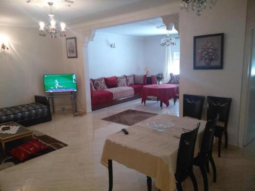 a living room with a table and a red couch at Apartment Centre Meknes in Meknès