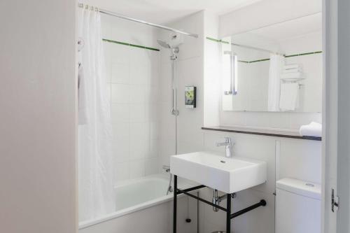 La salle de bains blanche est pourvue d'un lavabo et d'une douche. dans l'établissement Sure Hotel by Best Western Châteauroux, à Le Poinçonnet