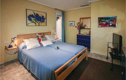 Schlafzimmer mit einem Bett mit blauer Bettwäsche und einem TV in der Unterkunft Awesome Apartment In Santa Pola With Kitchenette in Santa Pola