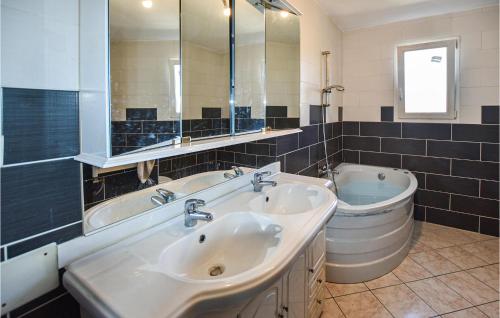 een badkamer met 2 wastafels, een bad en een spiegel bij Stunning Home In Baix With Outdoor Swimming Pool in Baix