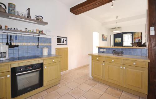 a kitchen with yellow cabinets and blue tiles on the wall at Mas Melusine in Caderousse