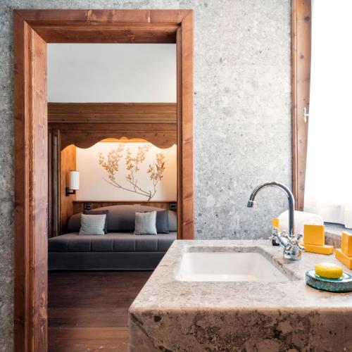 a kitchen with a sink and a couch in the background at Faloria Mountain Spa Resort in Cortina dʼAmpezzo