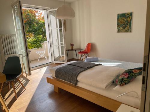 1 dormitorio con 1 cama y balcón con mesa y sillas en au jardin, en Zuchwil