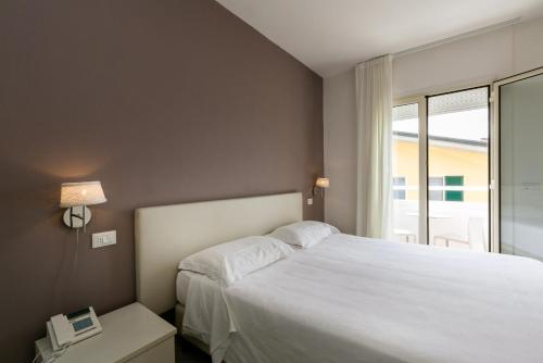 a bedroom with a large white bed and a window at Hotel Saviola in Sirmione