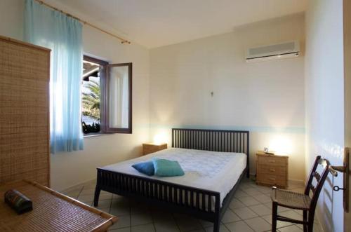 a bedroom with a bed and a window and a chair at Villa Levante vista mare Cornino in Custonaci