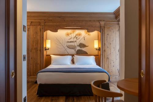 a bedroom with a bed with a painting on the wall at Faloria Mountain Spa Resort in Cortina dʼAmpezzo