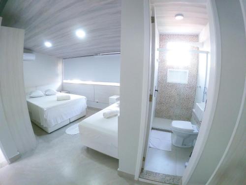 Habitación blanca con 2 camas y aseo en Ilha Flat Boganville, en Abraão