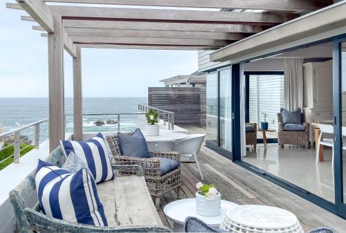 a patio with chairs and tables and the ocean at Le Paradis Penthouse in Hermanus