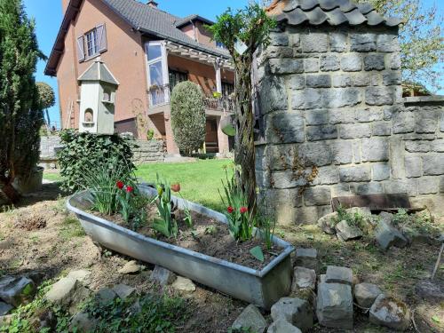 a garden in front of a house with a stone wall at Chambres chez Nanou avec petit déjeuner in Chimay