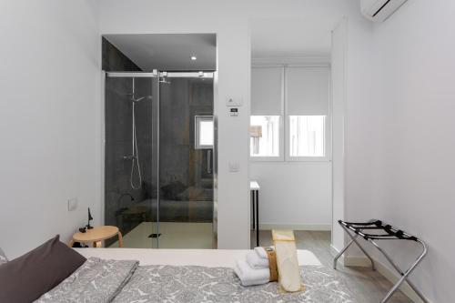 a white room with a bed and a shower at Alma Suites Madrid CH in Madrid