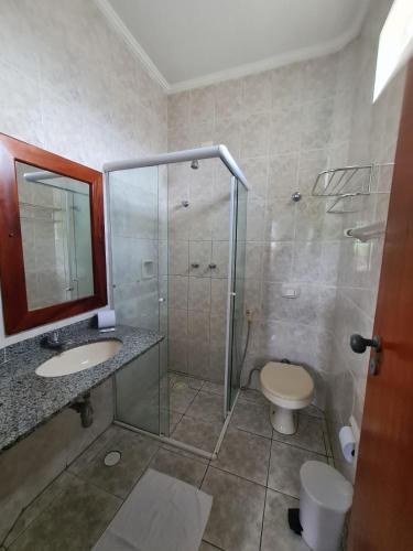 a bathroom with a shower and a toilet and a sink at Pousada Porto do Itagua in Ubatuba