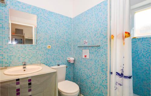 バスティアにあるCozy Apartment In Bastia With Kitchenetteの青いタイル張りのバスルーム(トイレ、シンク付)