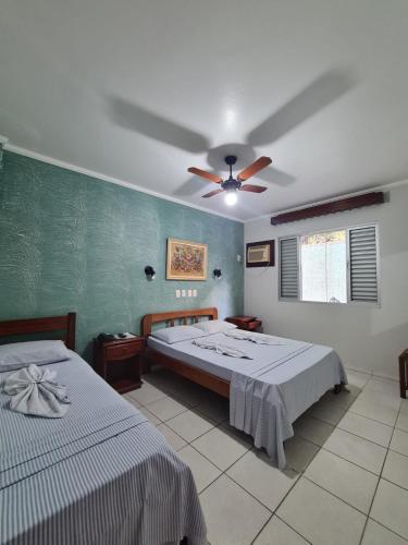 a bedroom with two beds and a ceiling fan at Pousada Porto do Itagua in Ubatuba